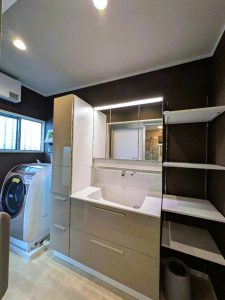 洗面化粧台はタッチレス水栓を設置。ラフな質感の壁紙。トールキャビネットと見事に調和しています